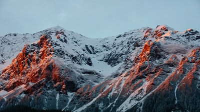 多云的天空中被雪覆盖的山的照片